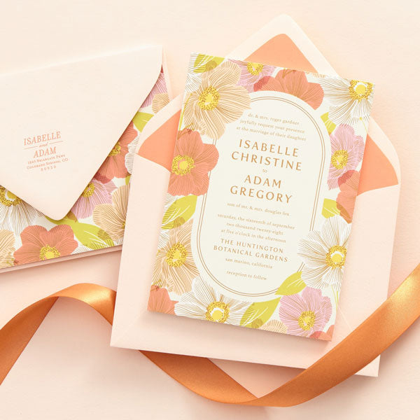 A coral, pink and yellow floral wedding invitation and envelope.