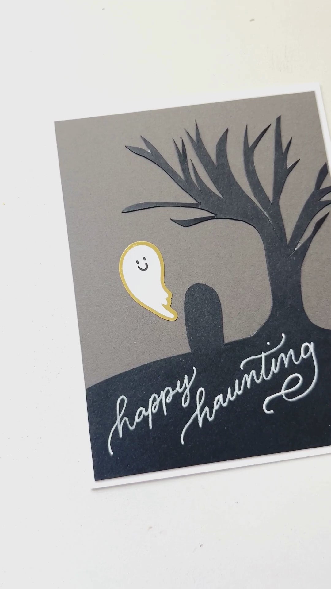Video displaying how to DIY a ghost cemetery greeting card with paper and stickers.