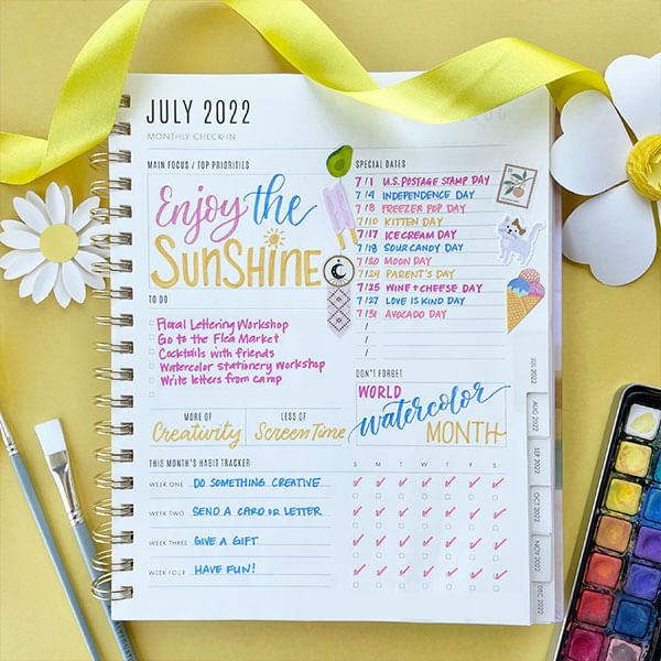 Planner opened to July, displaying decorations for notable events.