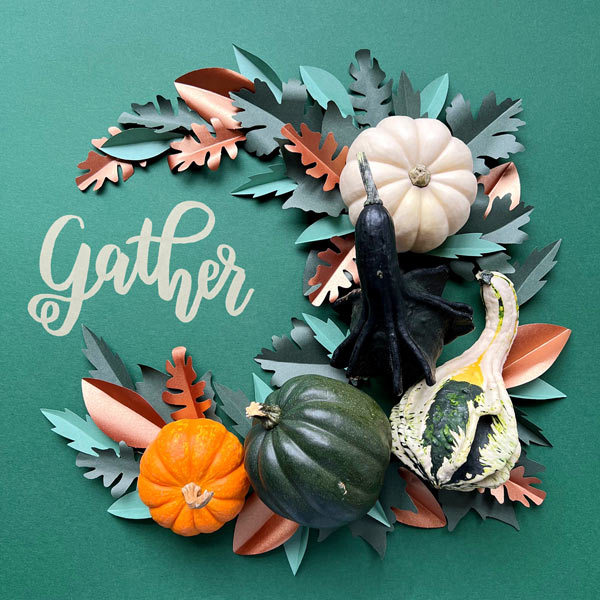 A stunning hand crafted paper wreath with gourds surrounding the word Gather.