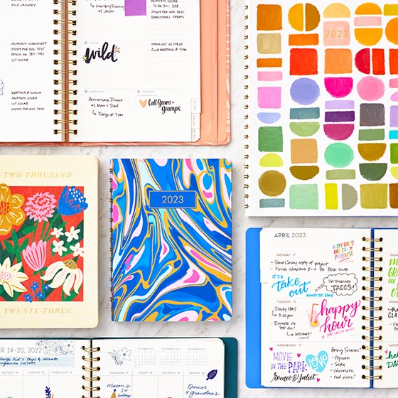 New planners with bright and colorful covers and open pages covered in writing.